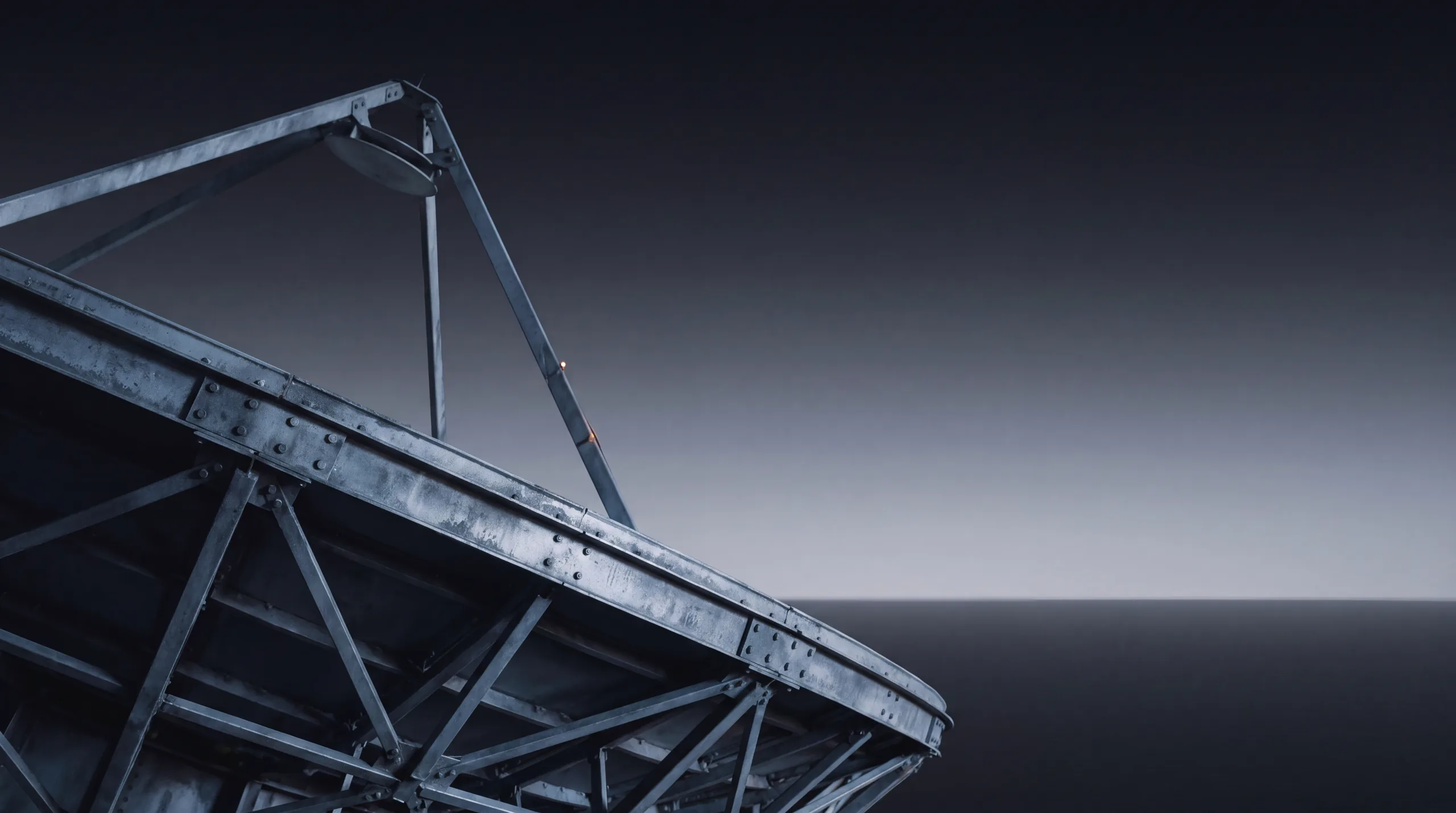 A steel radio-telescope truss angled against a graduated dusk sky over still water.