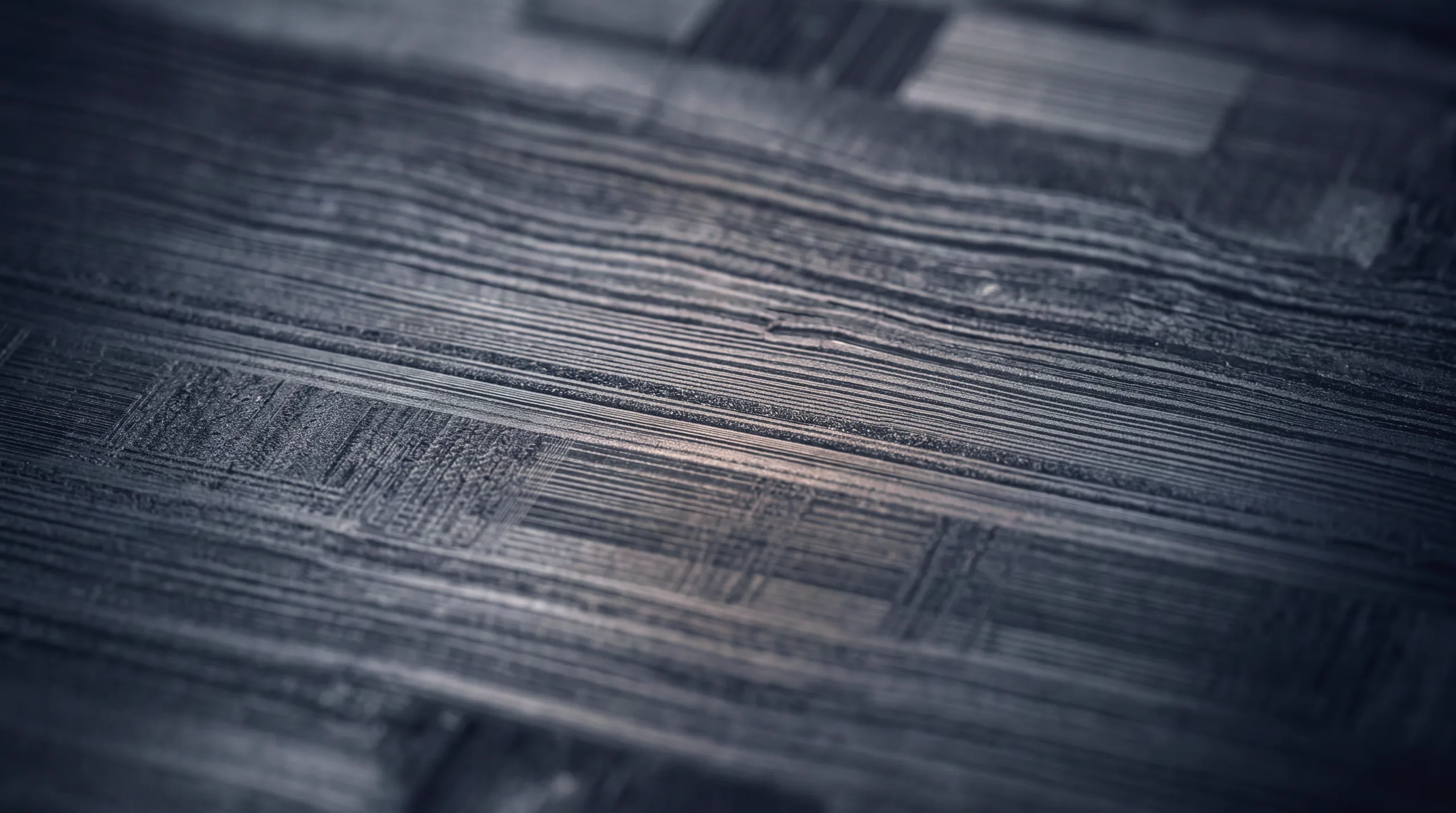 Macro view of a machined dark metal surface, tool marks running in parallel grain.