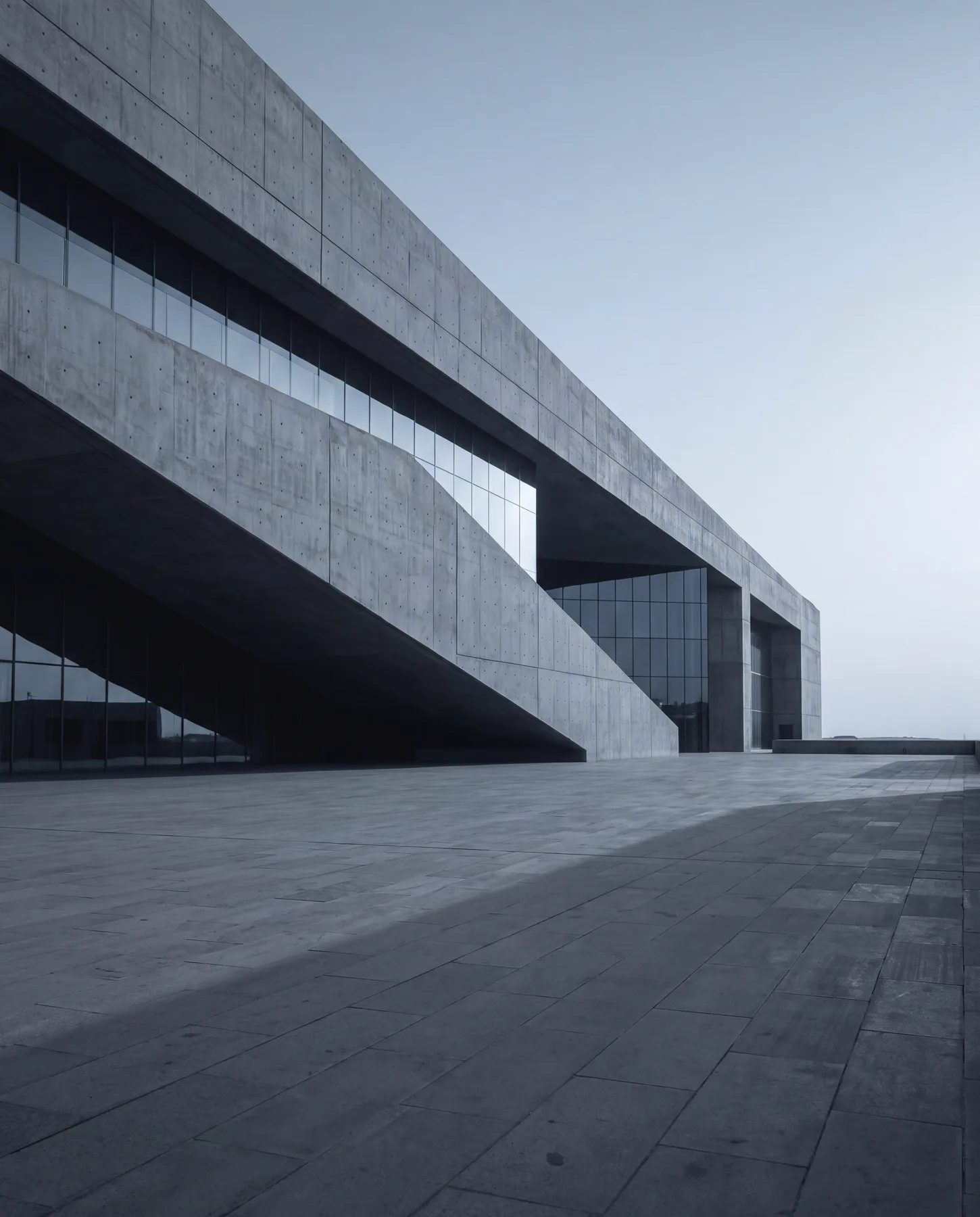 A cantilevered concrete building at dawn, its plaza empty and raked with light.