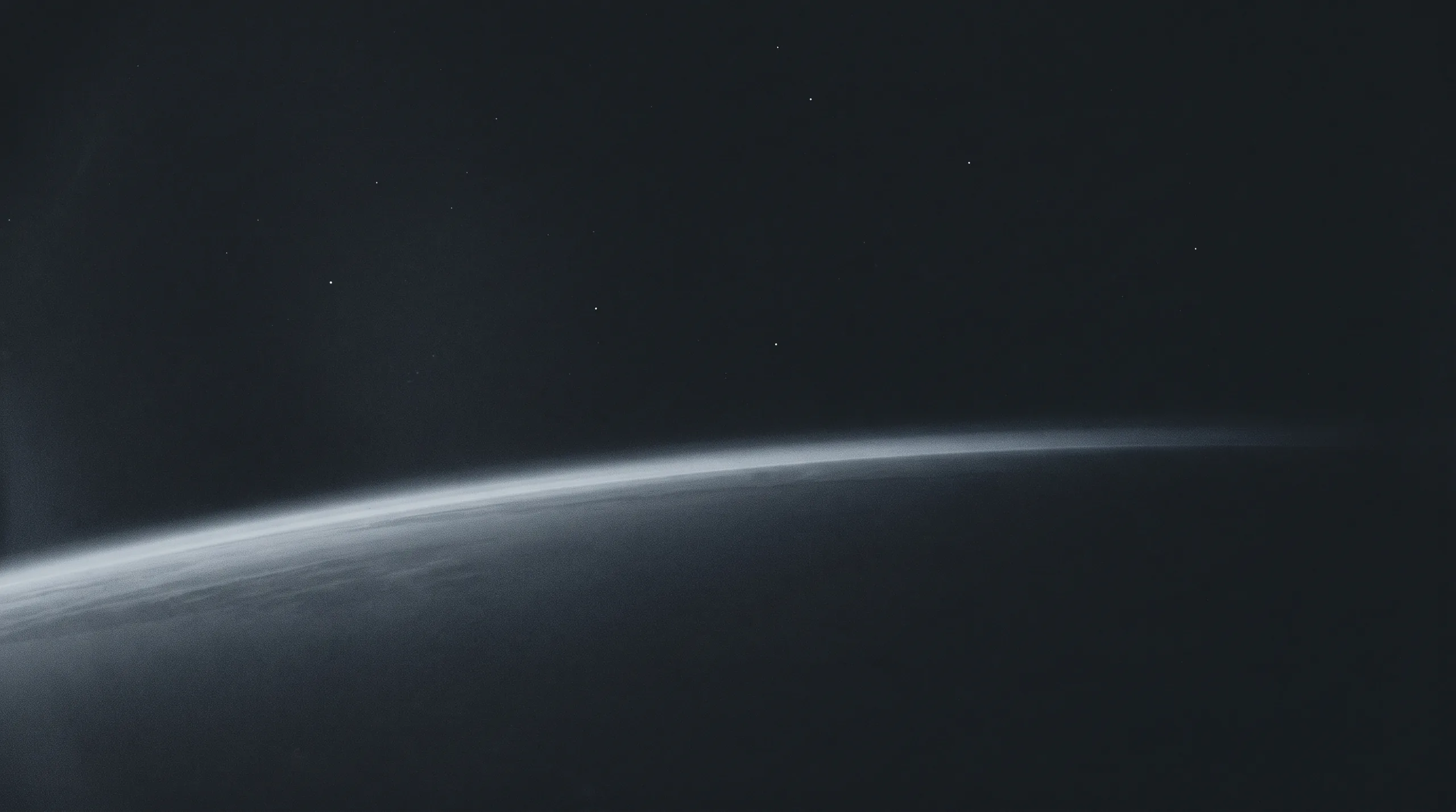The curved limb of a planet seen from orbit, lit along one edge, a scattering of stars above it.